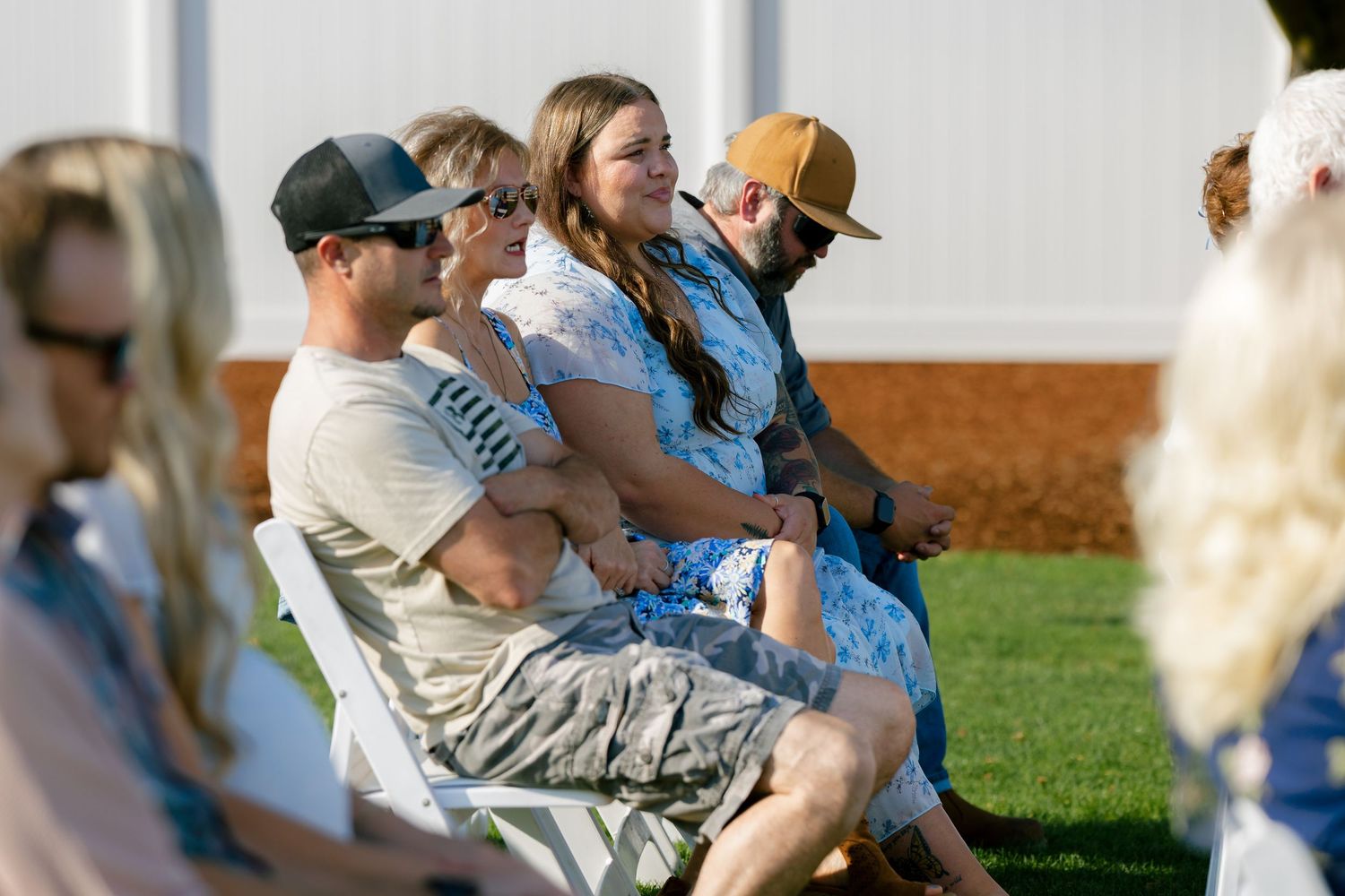 Wedding guests gathered outdoors in casual attire enjoying a sunny celebration.
