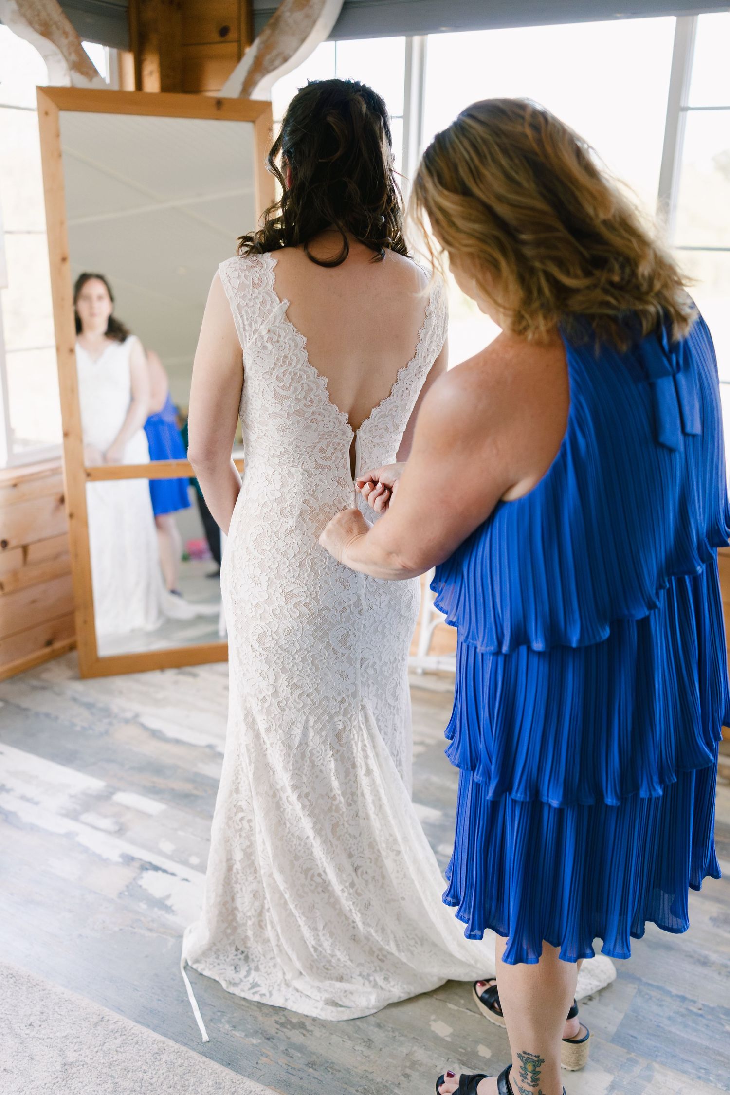 Wedding party wearing white lace and royal blue dresses in a rustic indoor setting.
