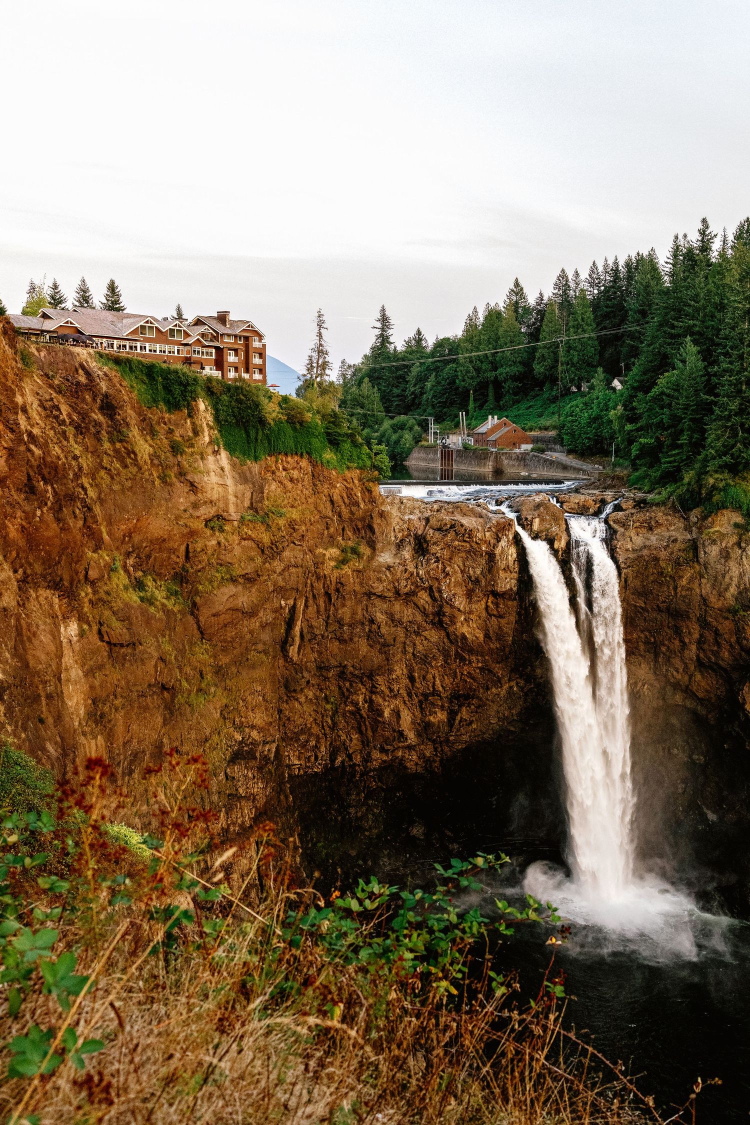 Dramatic waterfall cascades down rocky cliffs near Salish Lodge at Snoqualmie Falls in Washington State.