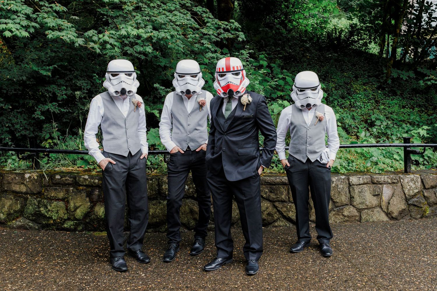 Wedding party wearing Star Wars stormtrooper masks pose against green forest background.