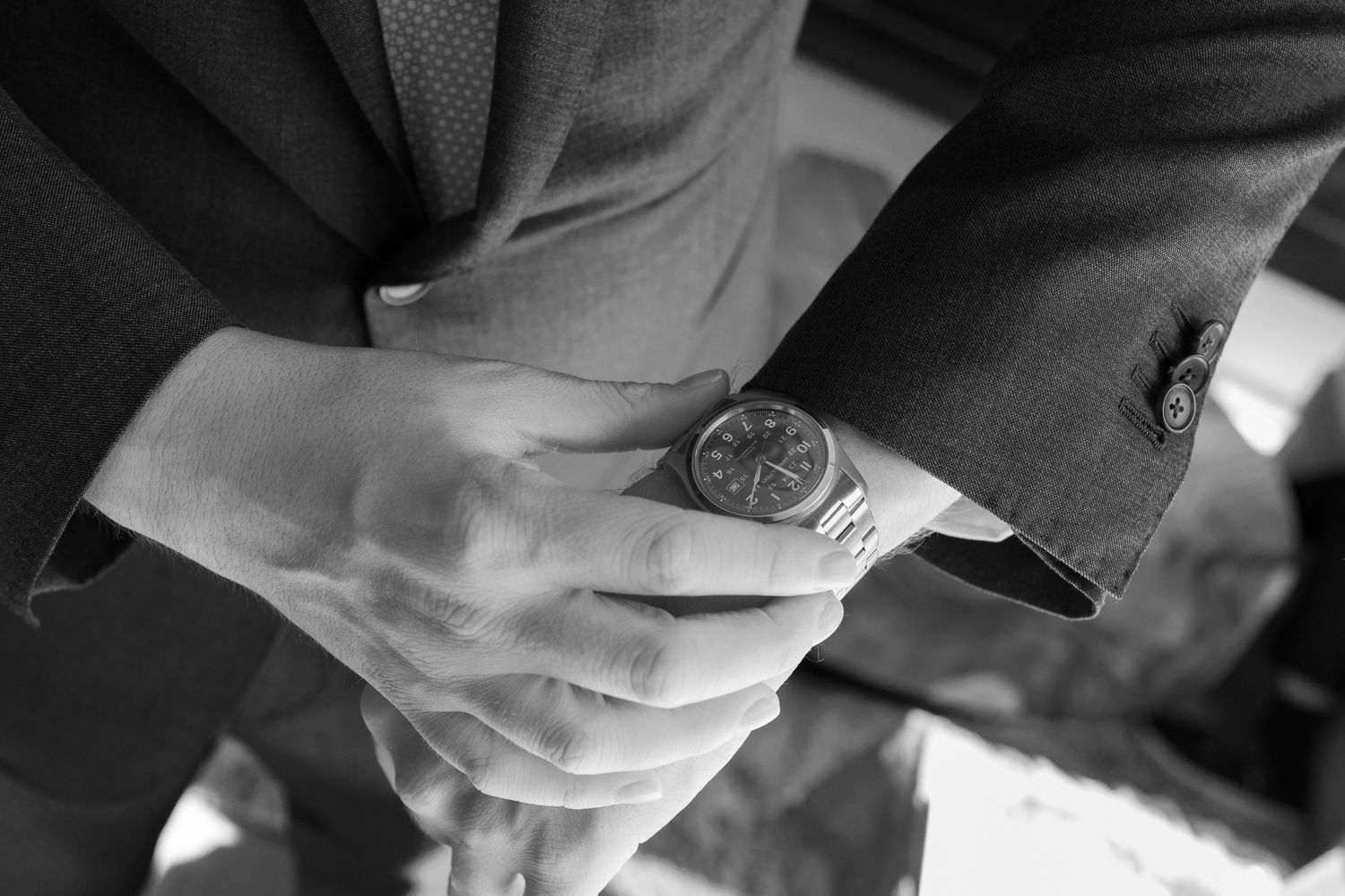 Black and white close-up of hands clasped together during a wedding ceremony.