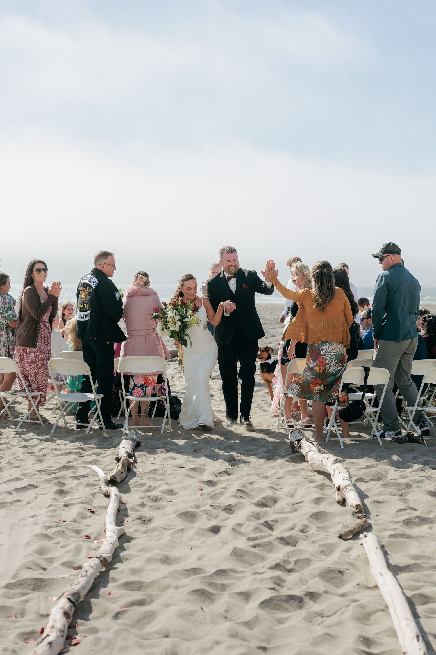 Beach wedding ceremony setup with guests seated on chairs in the sand.
