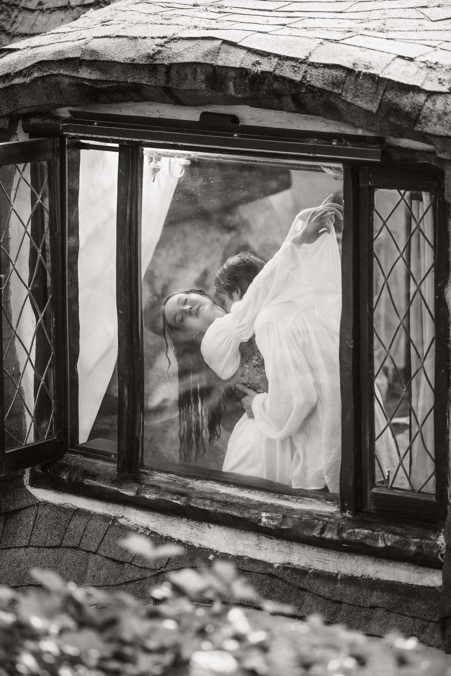 A black and white photo showing a figure through diamond-paned windows.
