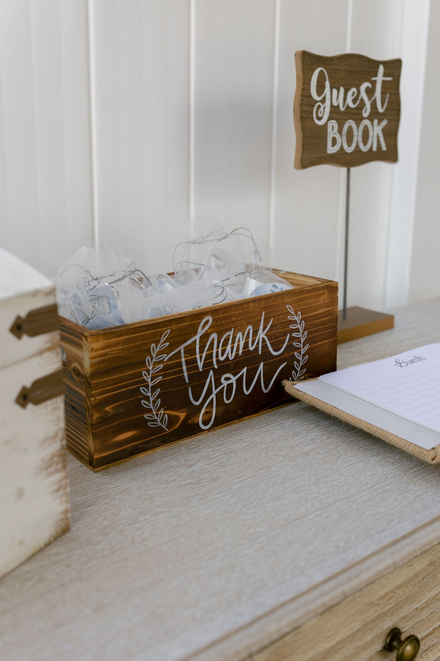 Rustic wooden guest book display with thank you sign at wedding reception.