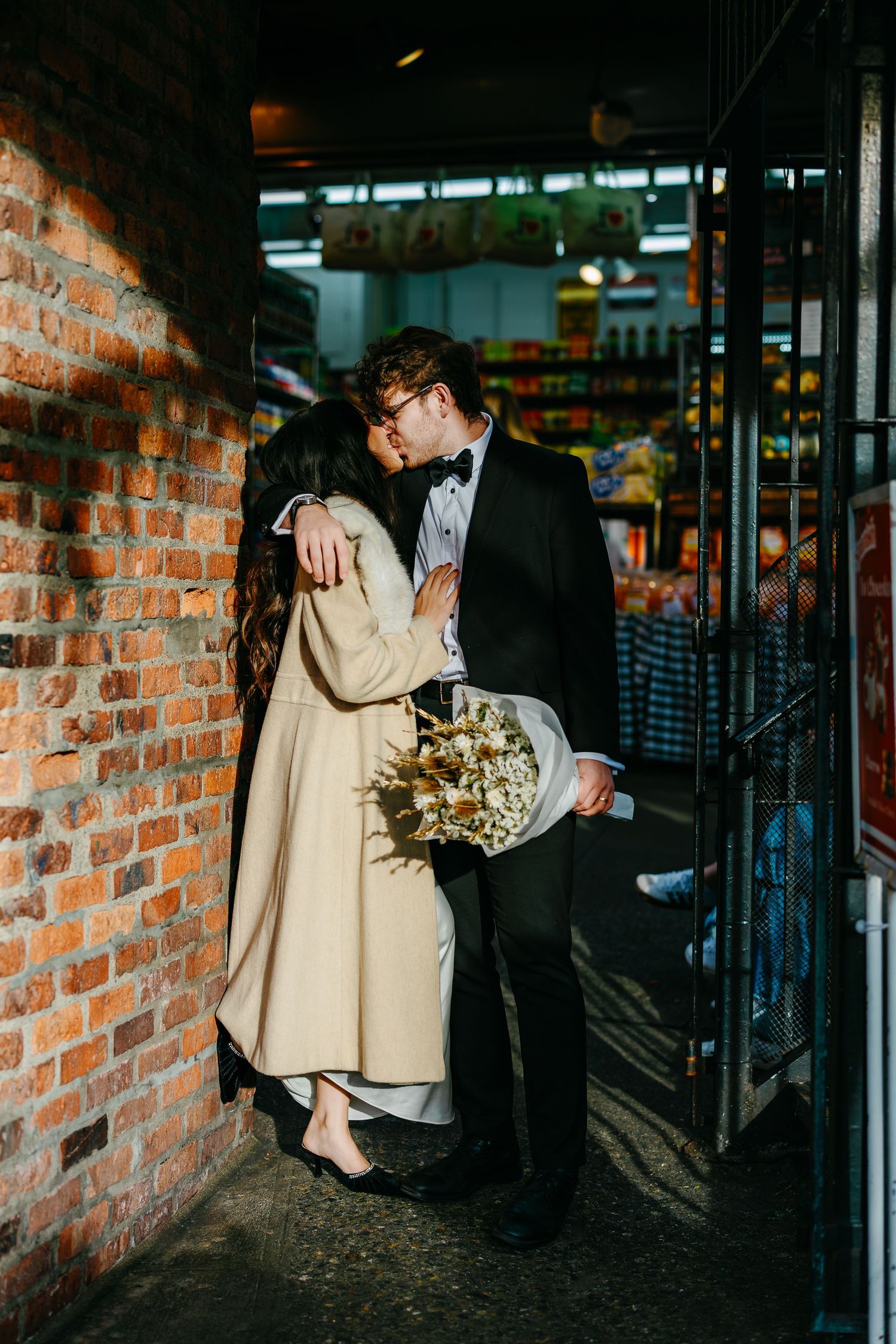 A couple shares an intimate moment against a rustic brick wall backdrop.