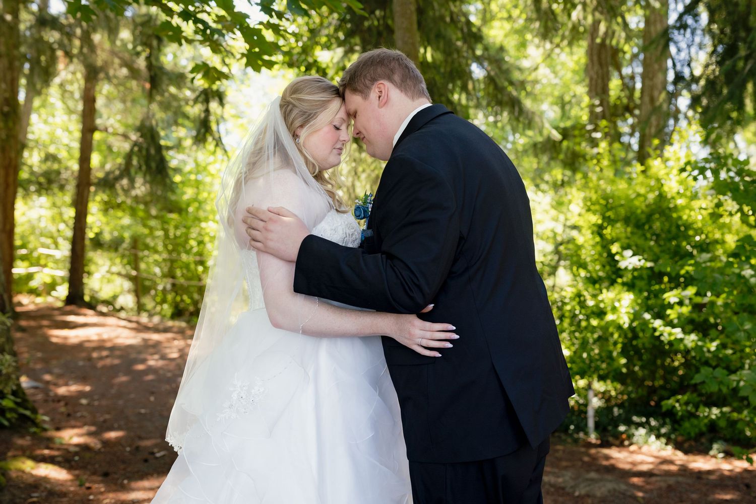 Bride and groom sharing a romantic moment in a lush green forest setting on their wedding day.