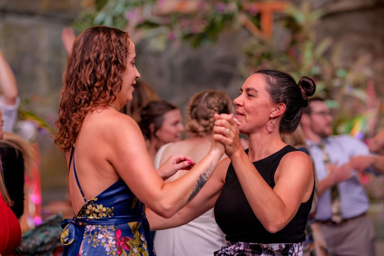 Two women sharing a joyful dance together at an outdoor wedding reception celebration.