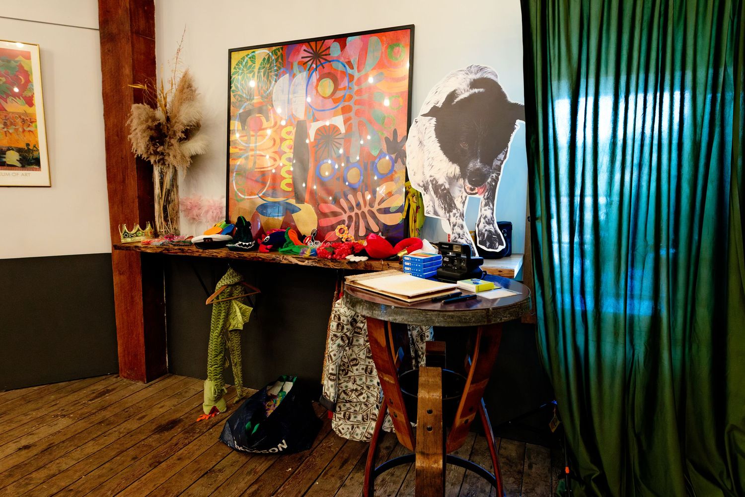 Colorful art installation with vibrant paintings displayed on a wooden console table in a rustic gallery setting.