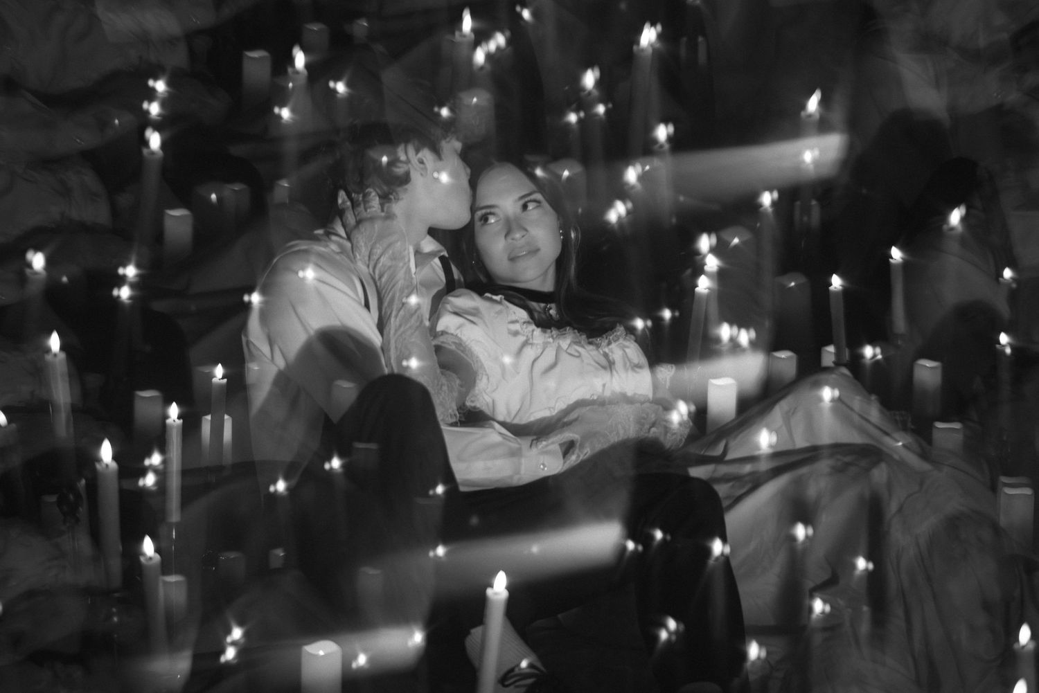 A black and white photo shows a couple dancing together in an intimate embrace under twinkling lights.