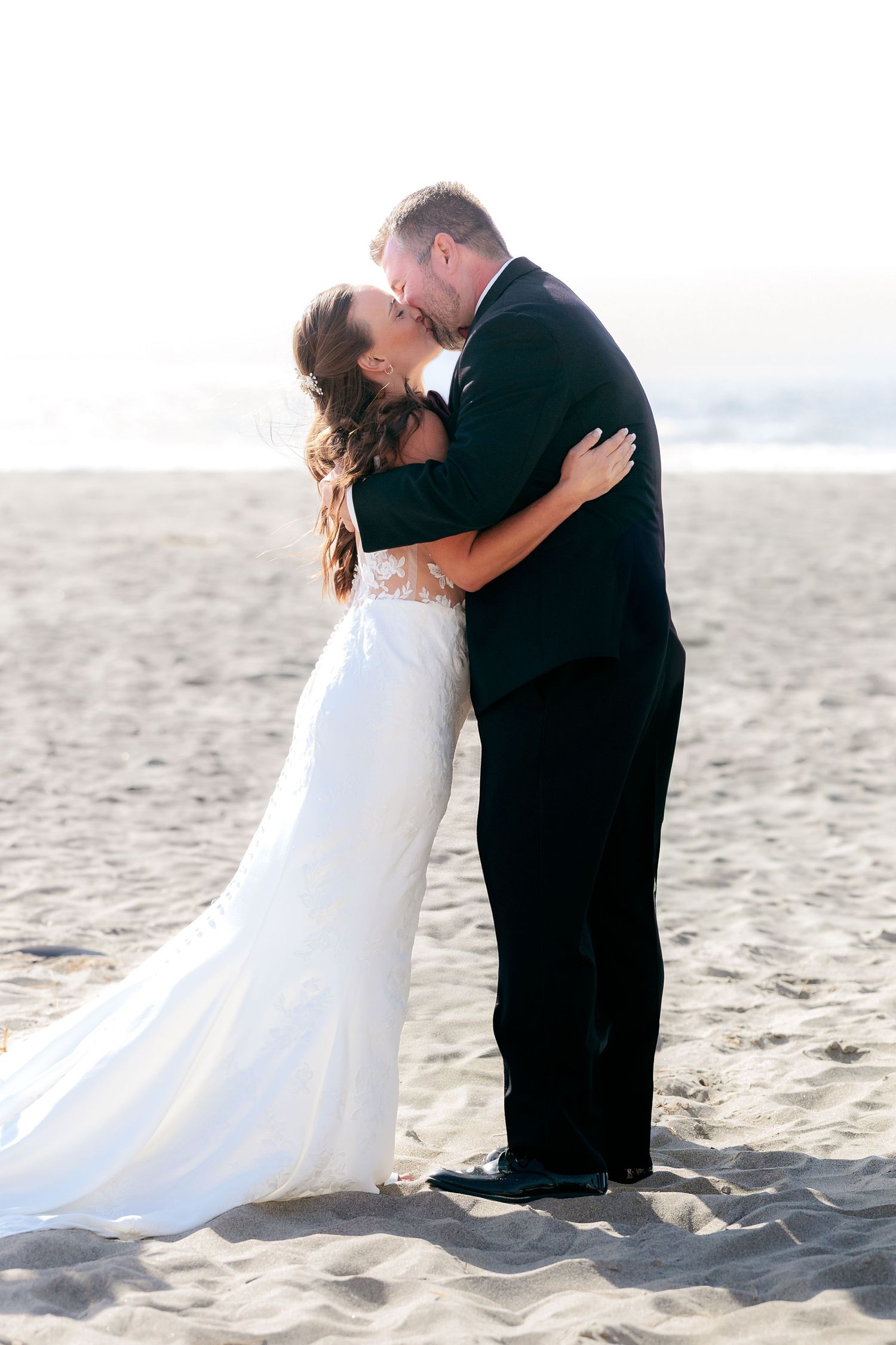 Romantic wedding photos on a sandy beach at sunset.