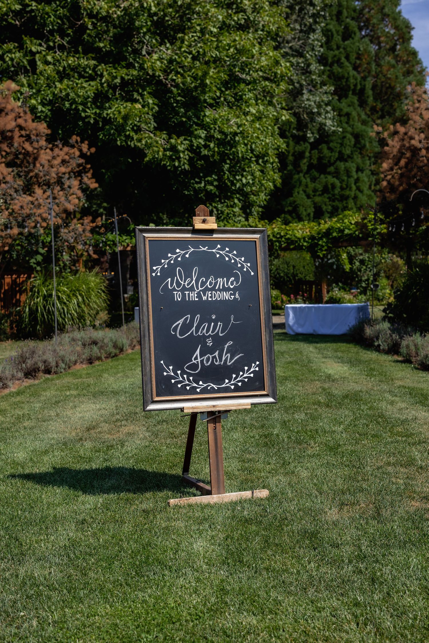 Wedding directional chalkboard signs displayed on wooden stands in a grassy outdoor venue.
