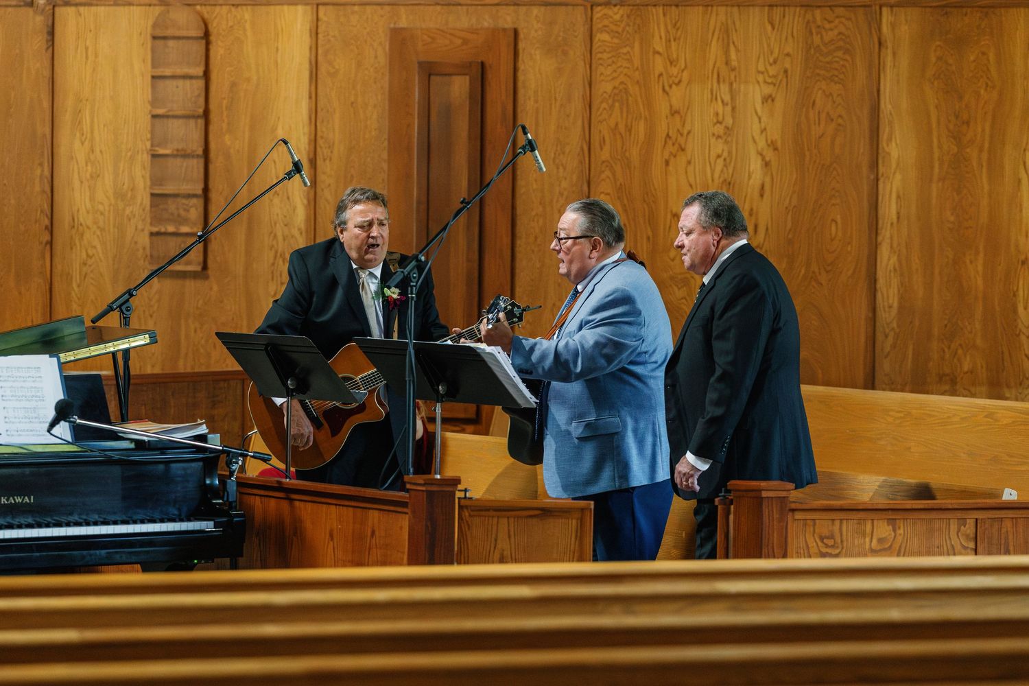 Musicians perform with instruments in a wood-paneled church sanctuary.