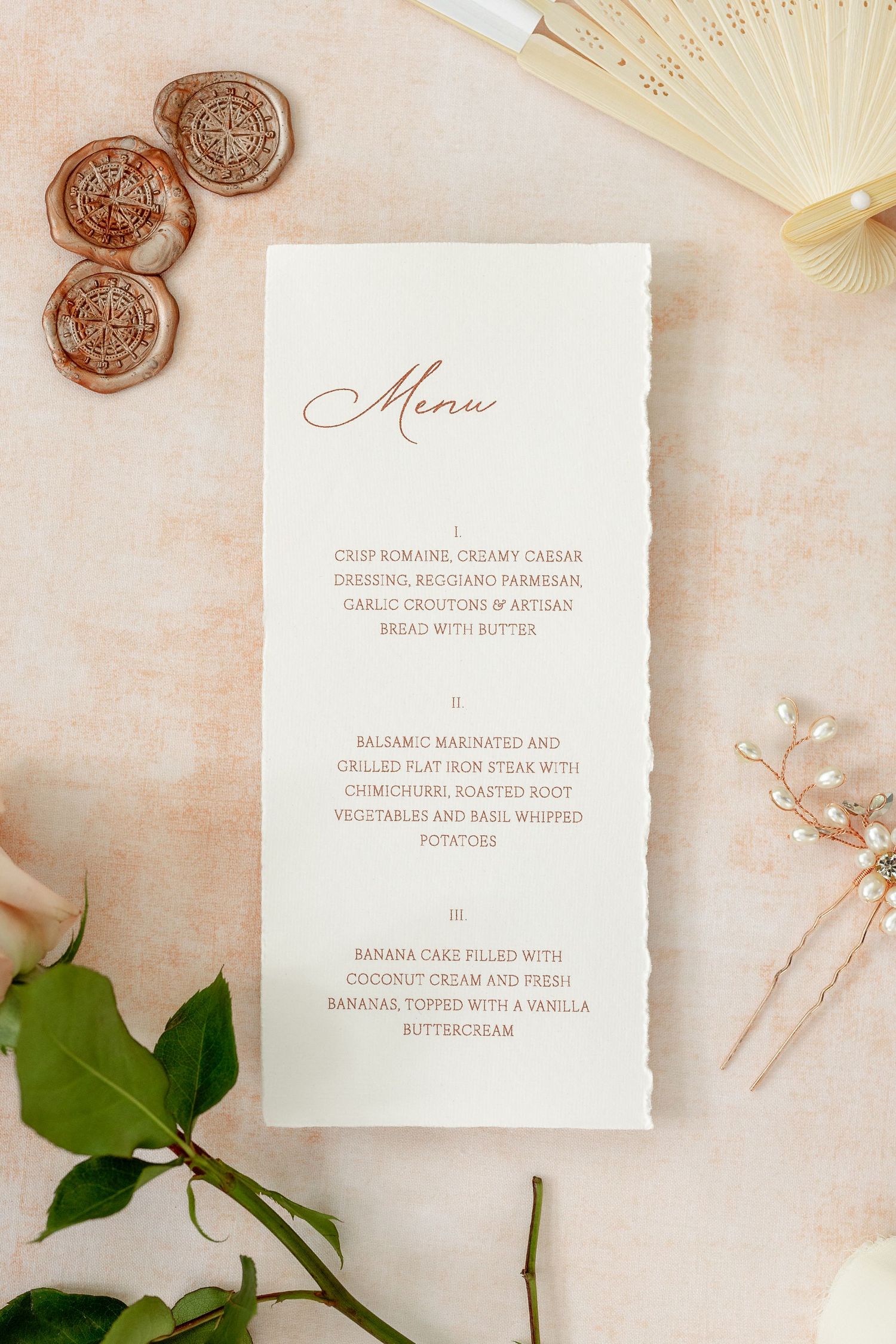 Elegant wedding menu card with copper wax seals and delicate floral details on blush background.