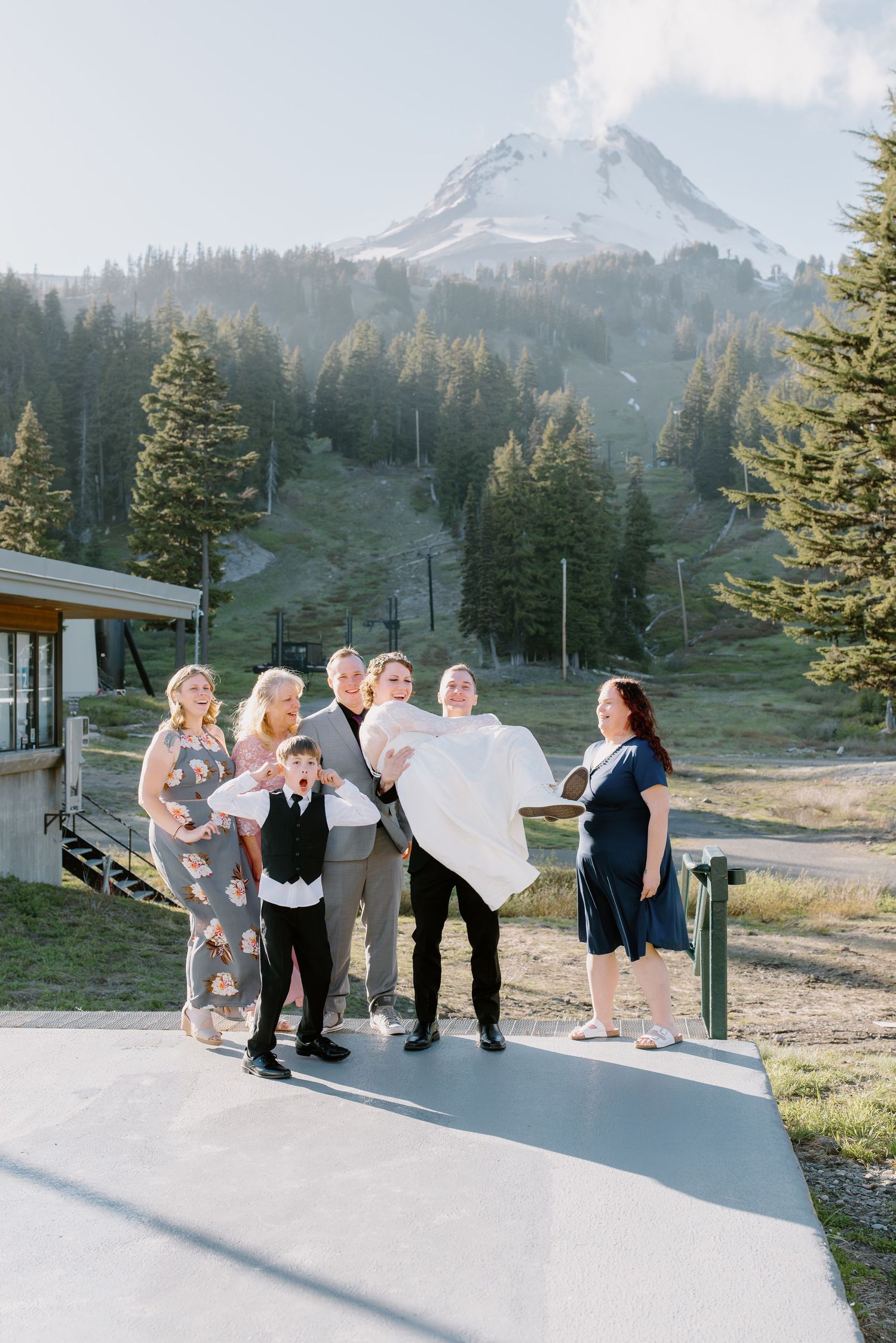 Wedding party posing with bride being lifted in front of Mt. Hood mountain and ski resort.