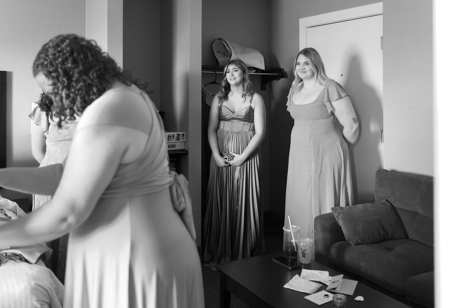 Black and white photo sequence showing bridesmaids getting ready in a room with dresses and preparations.