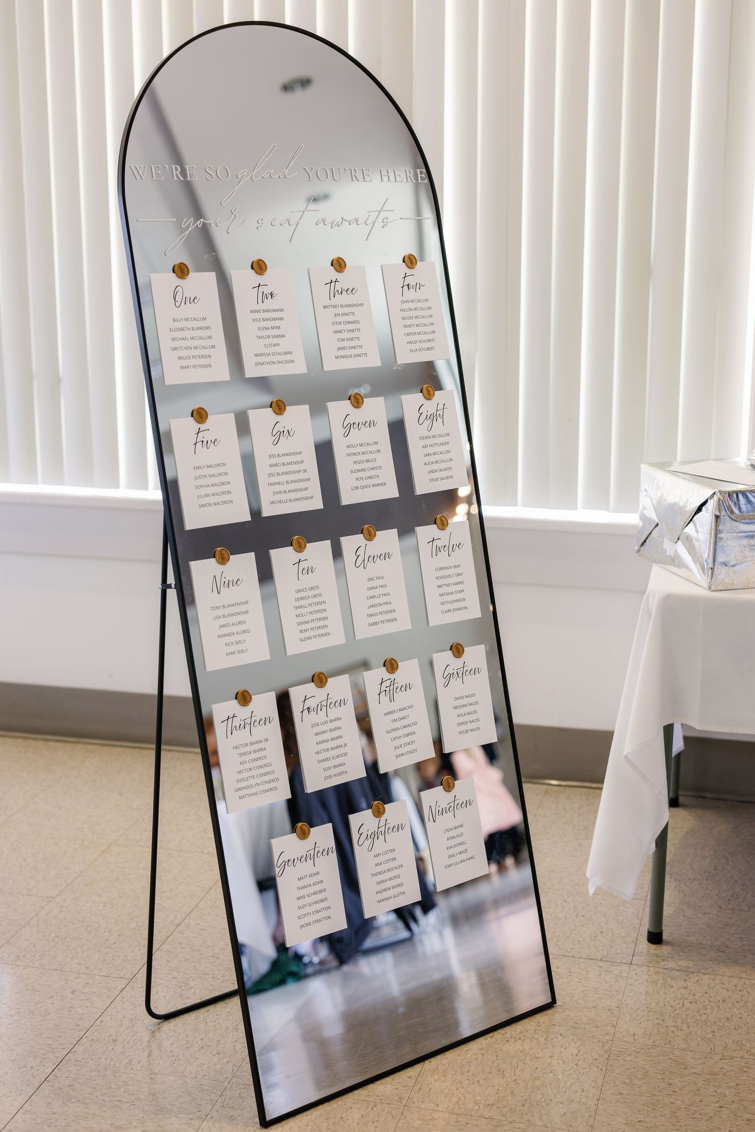 Mirror seating chart display with white cards and navy accents for wedding reception.