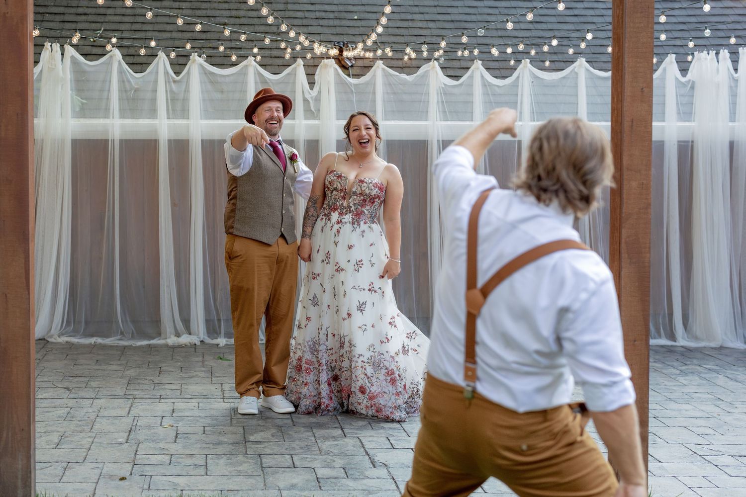 Wedding celebration scene with string lights and white curtain backdrop.