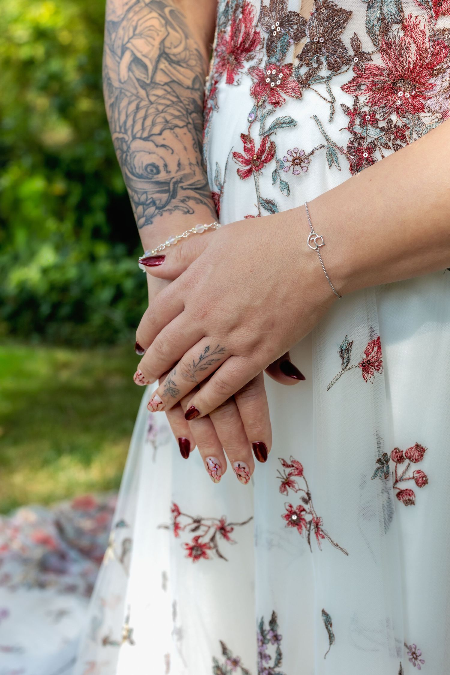 Close-up details of a white floral dress with red embroidered butterflies and flowers.