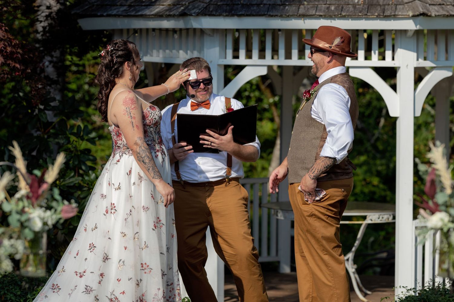 Wedding couple dances together outdoors in a romantic garden setting surrounded by greenery and white flowers.