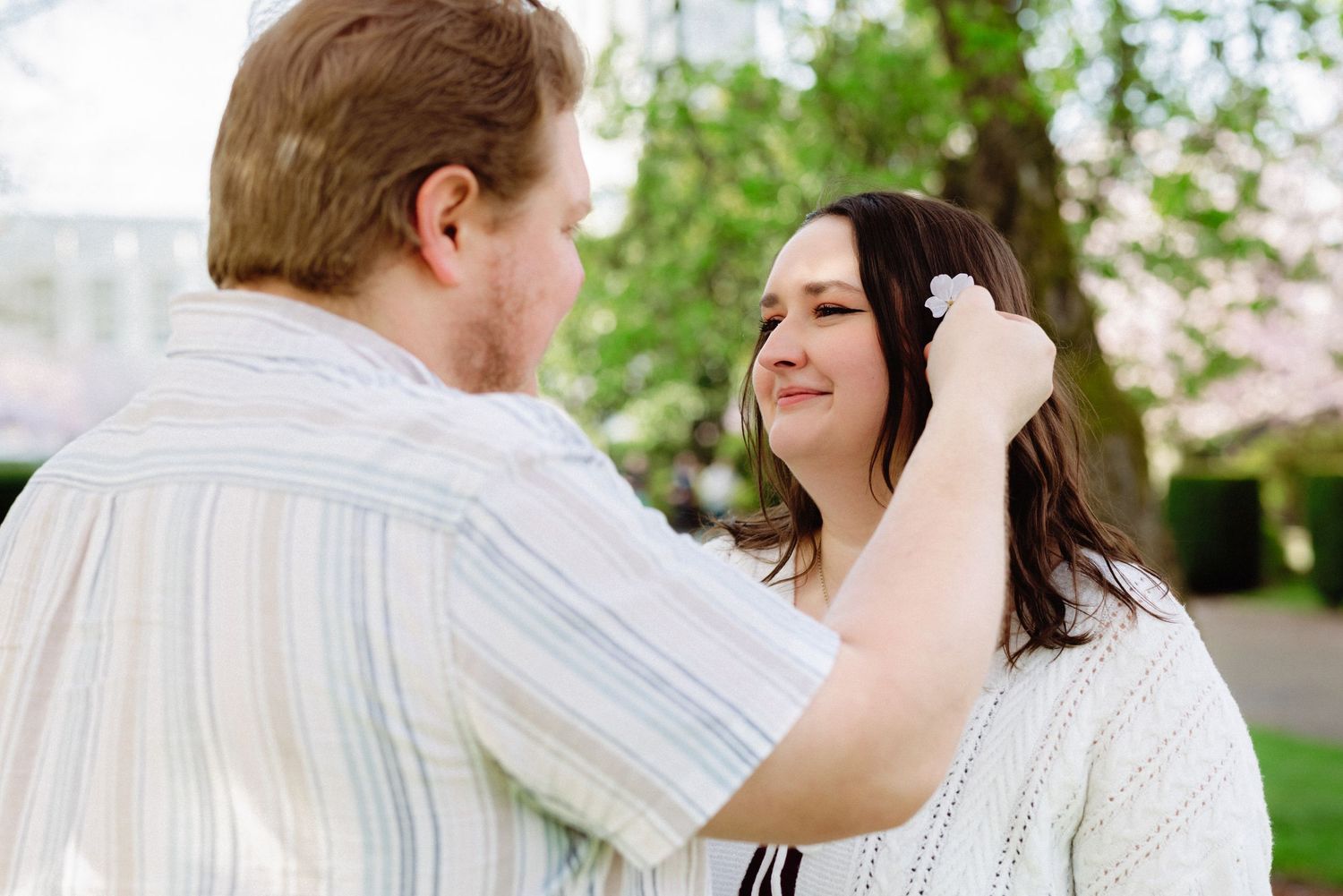 A couple shares an intimate moment together outdoors in a garden setting.