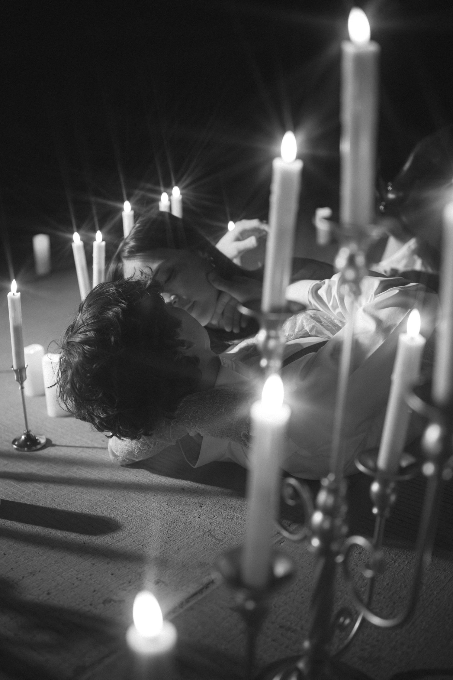 Black and white photo of candlelit scene with glowing tapered candles creating dramatic shadows.