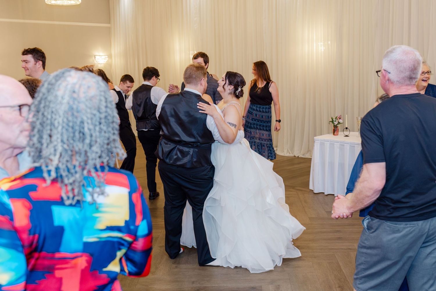 Bride and groom sharing a dance surrounded by guests at their wedding reception indoors.