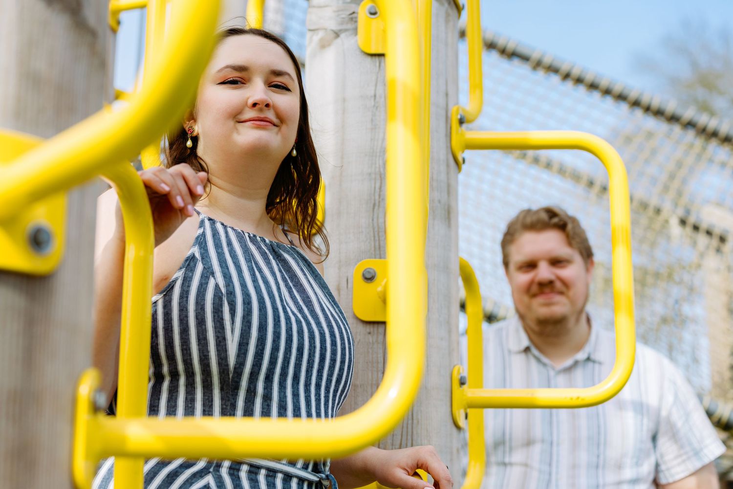 Group of people having fun on yellow playground equipment in an outdoor setting.