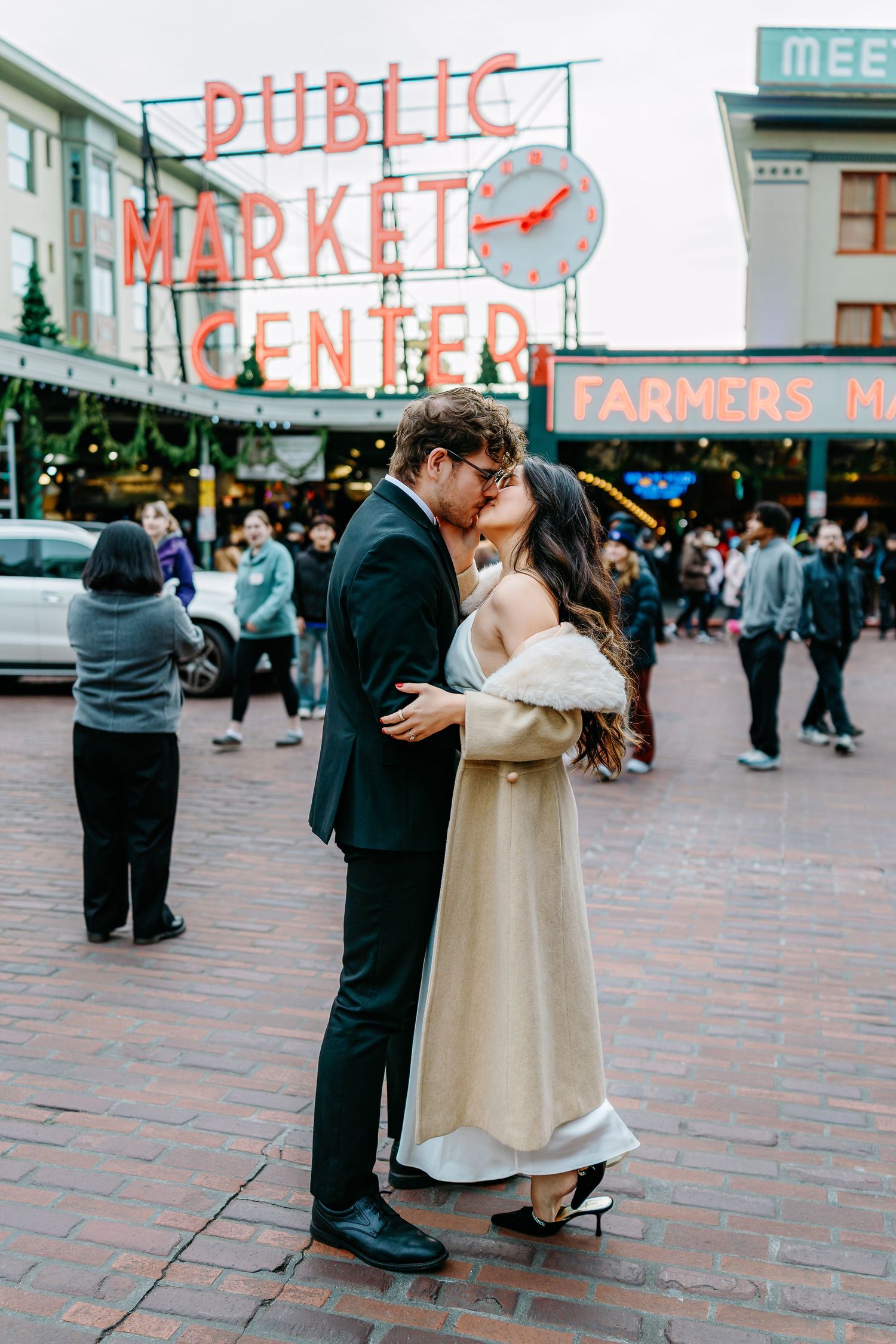 A romantic moment captured at Pike Place Market with the iconic sign visible in the background.