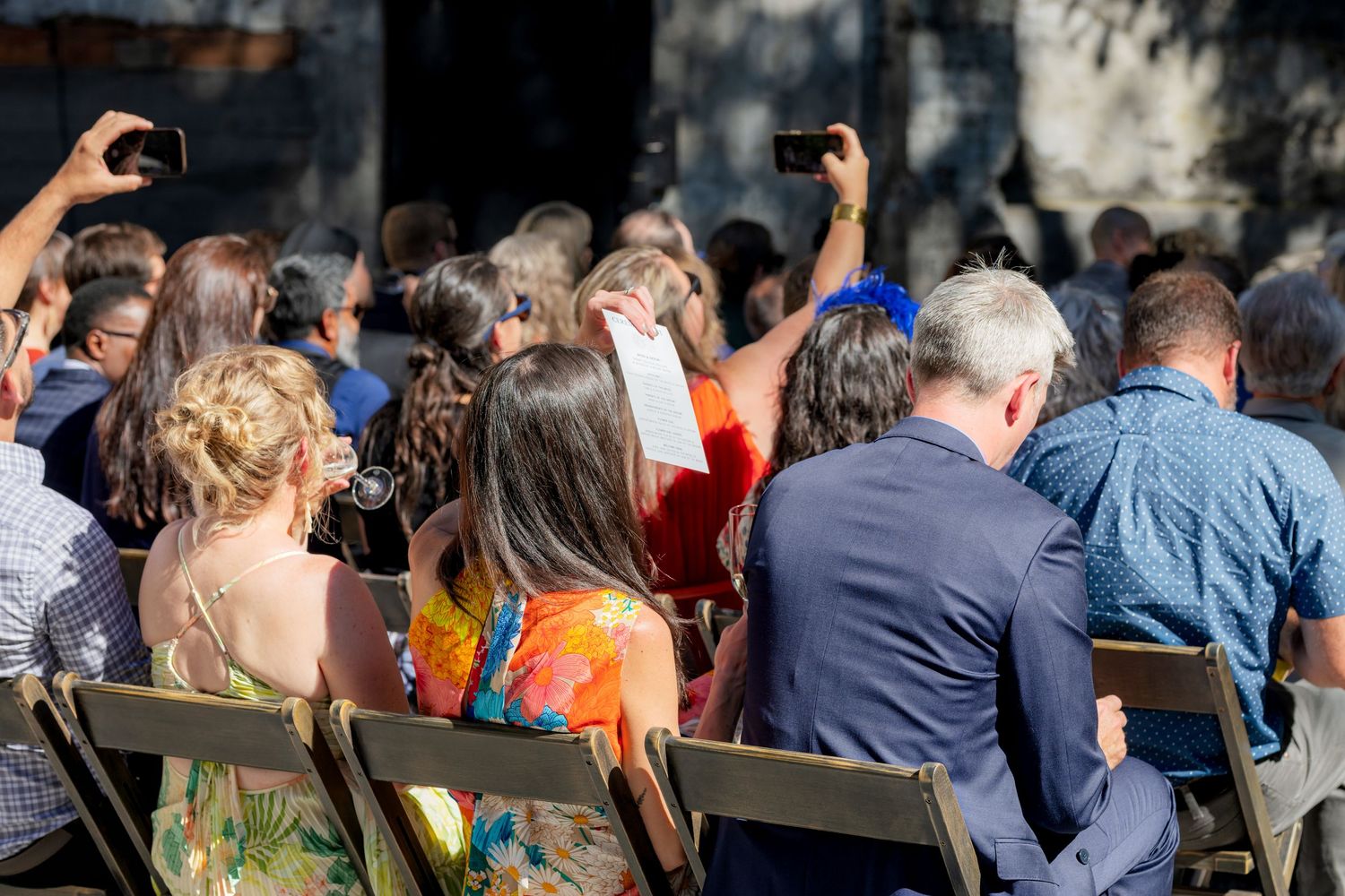 Wedding guests seated outdoors at ceremony.