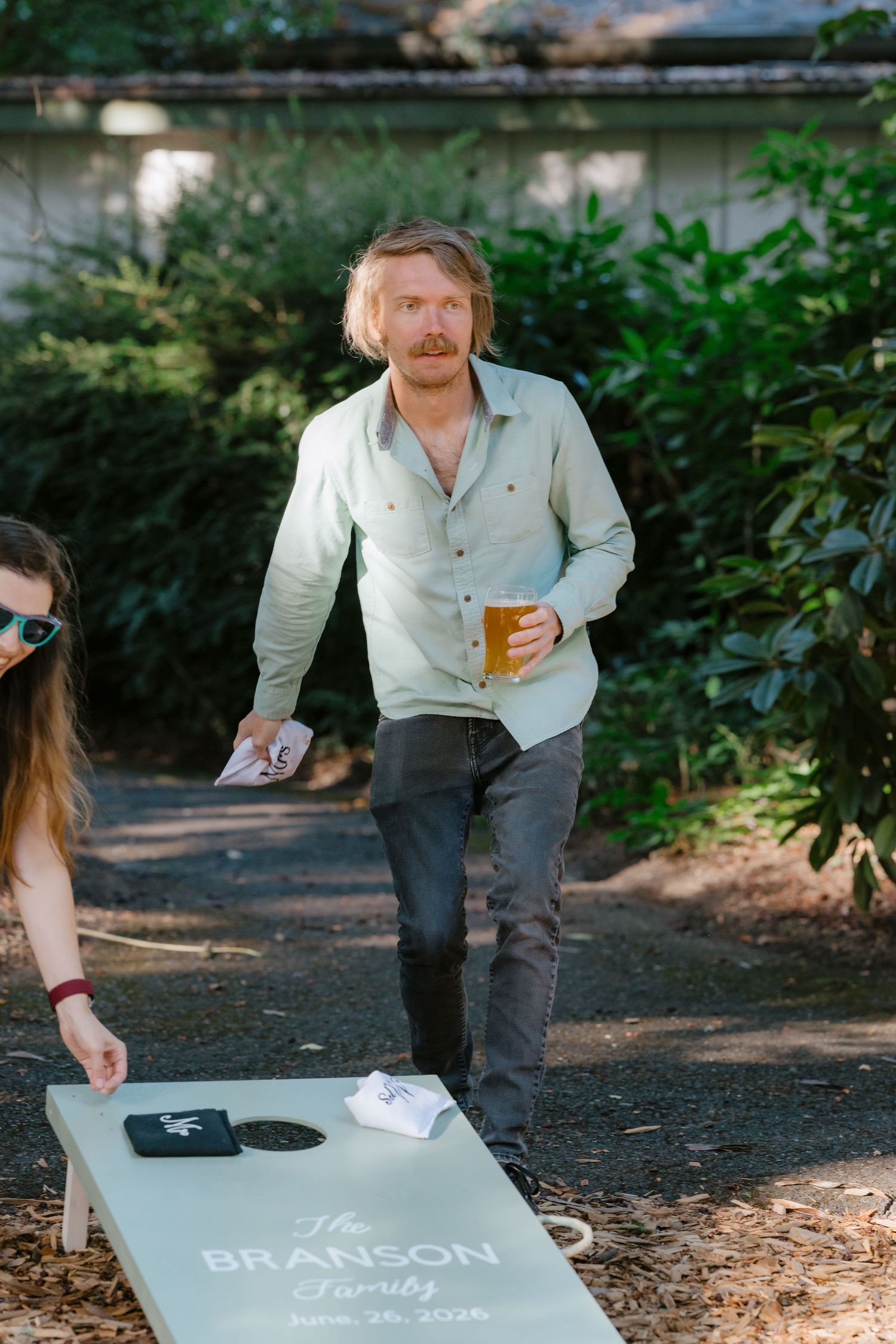 Guest plays cornhole at Branson family wedding reception outdoors.
