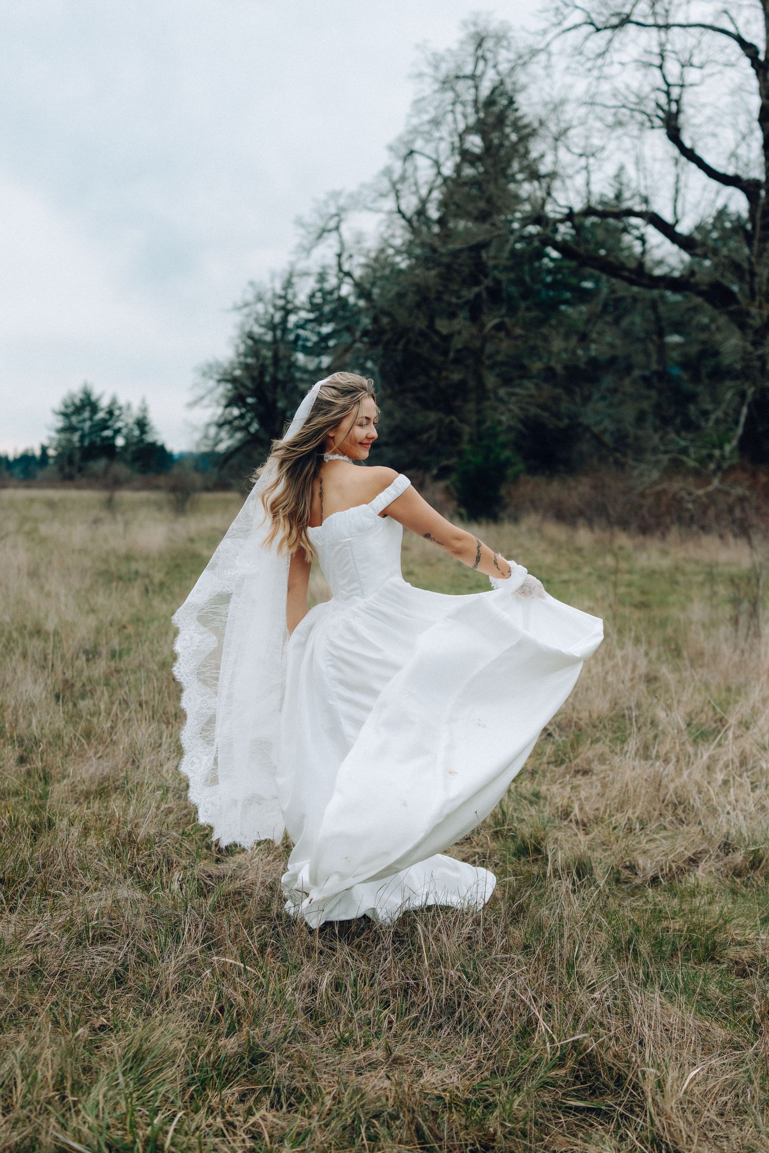 A flowing white dress twirls dramatically in the wind across a rustic field landscape.