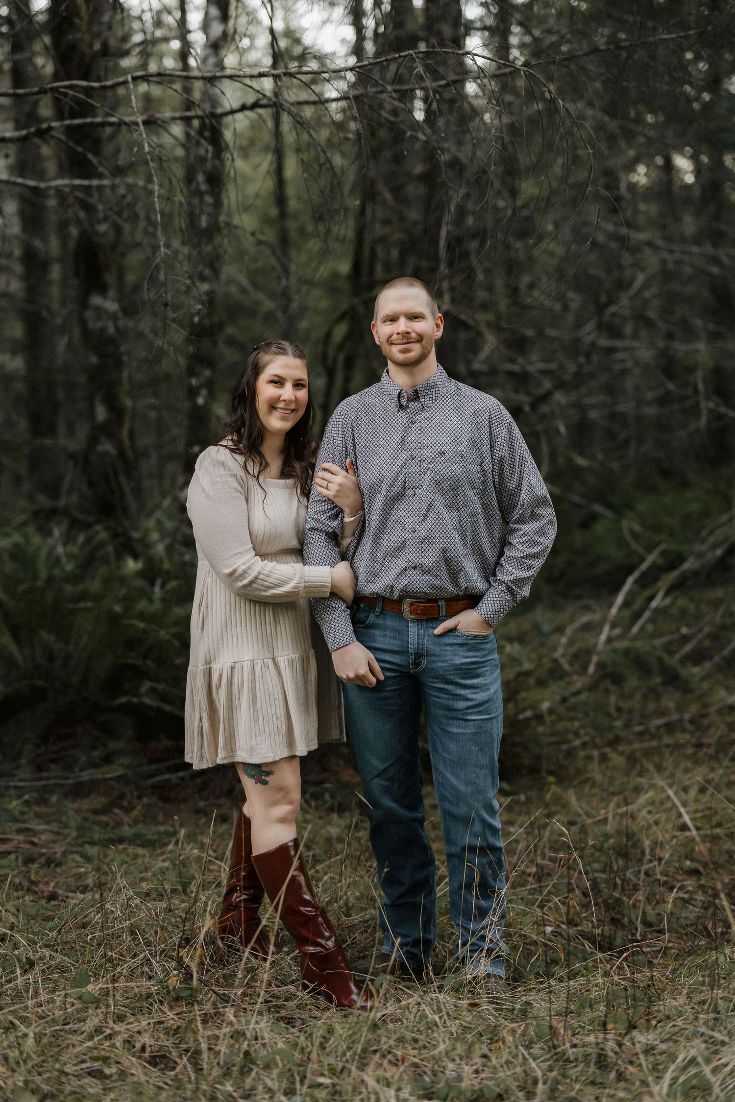 A casual couple's portrait session among tall trees in a natural wooded setting.