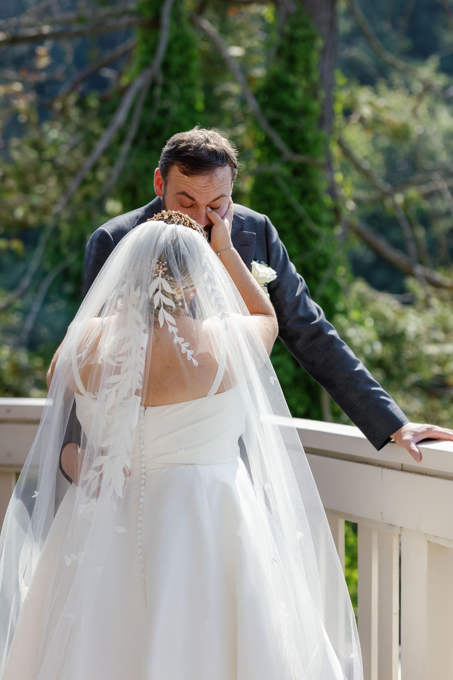 A tender first look moment between newlyweds on a white balcony with mountain views.
