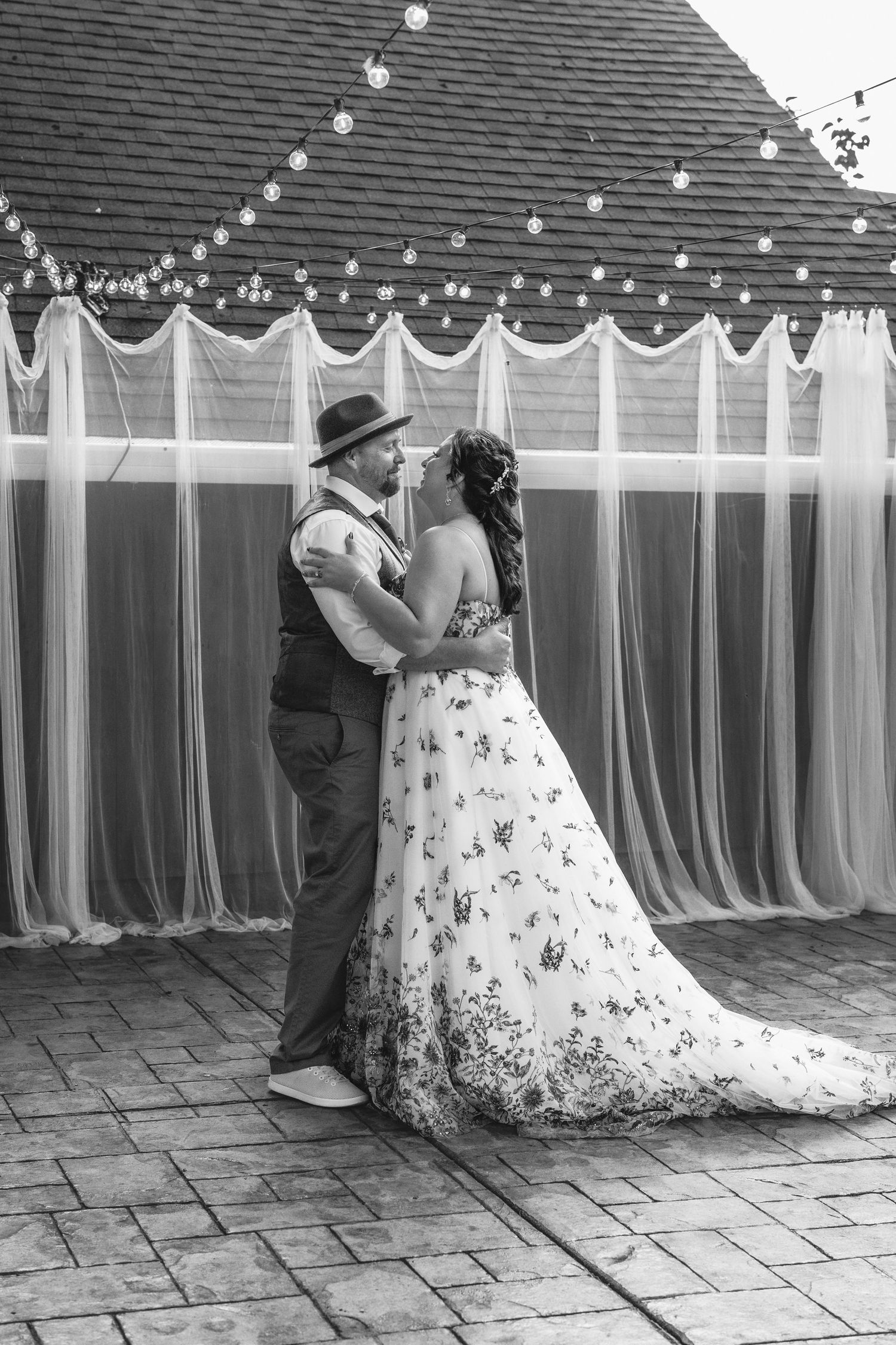 A romantic dance sequence under string lights at an outdoor wedding venue.