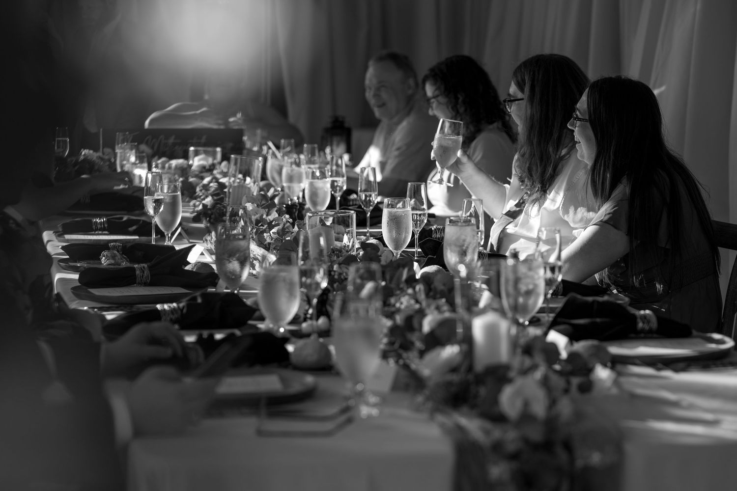 A black and white film sequence showing a vintage car and people gathered in a dimly lit scene.