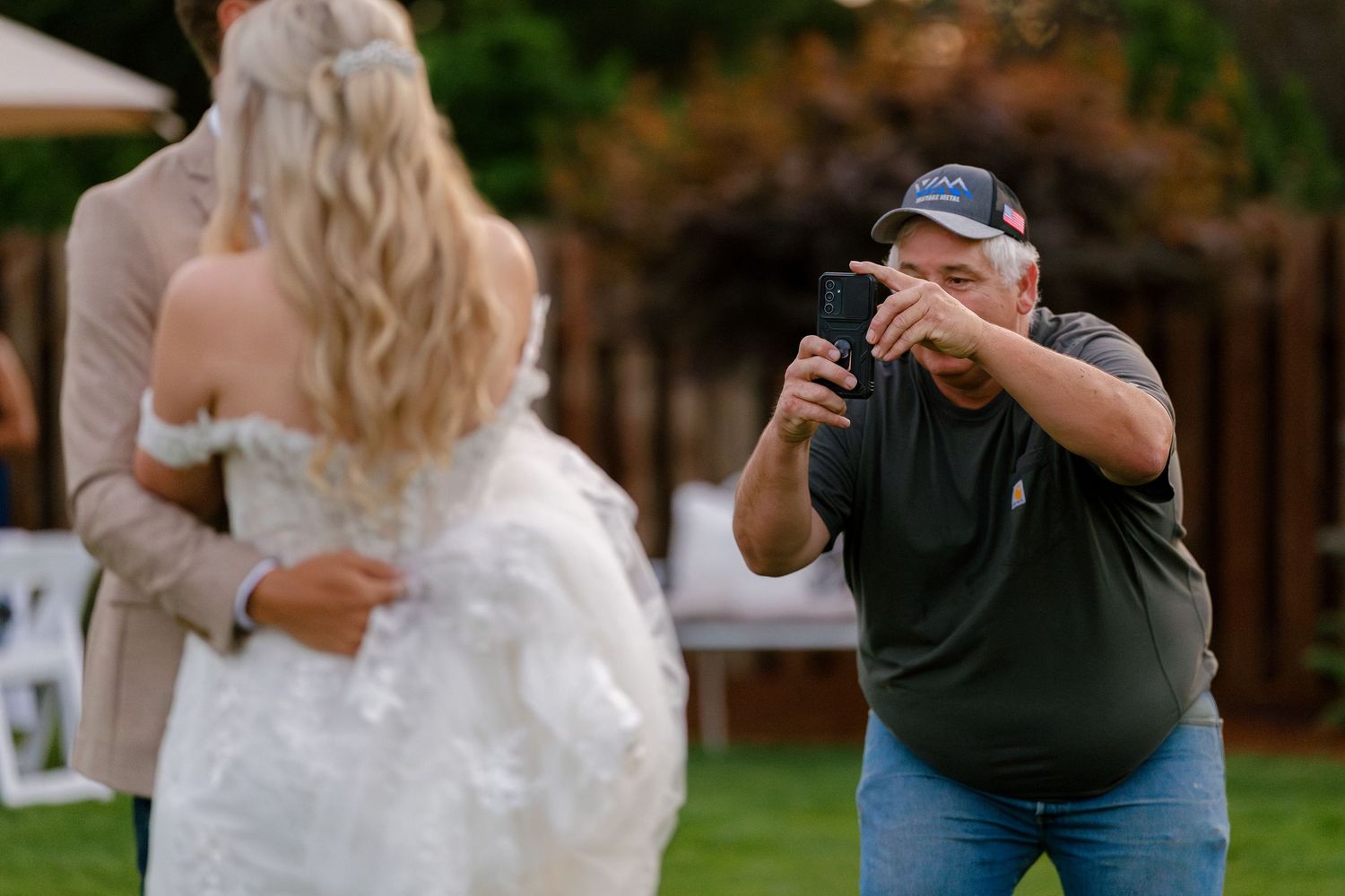 Photographer capturing moments at outdoor wedding reception in backyard setting.