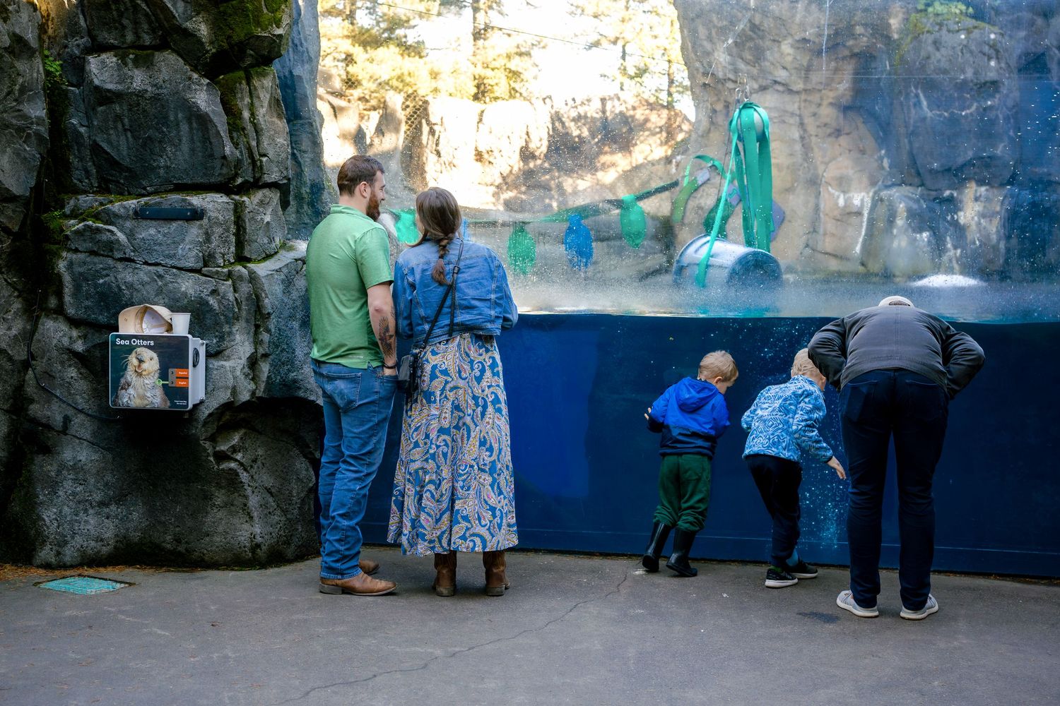 People viewing exhibits in a cave-like environment with blue-tinted lighting and rock formations.