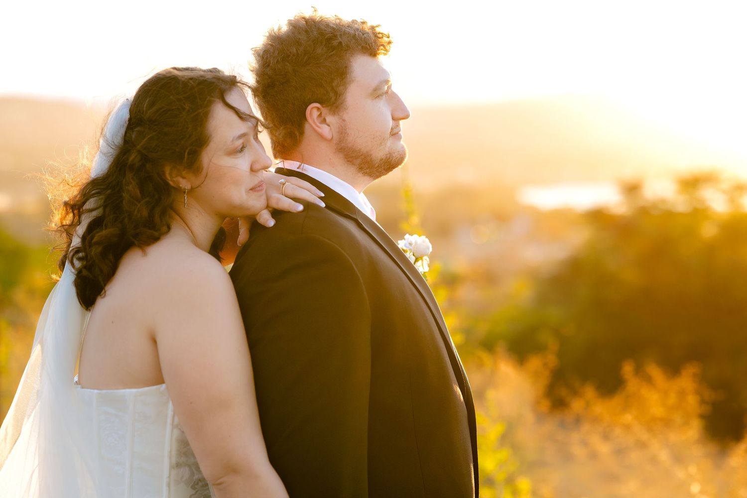 Newlyweds sharing a tender moment at sunset in their wedding attire.