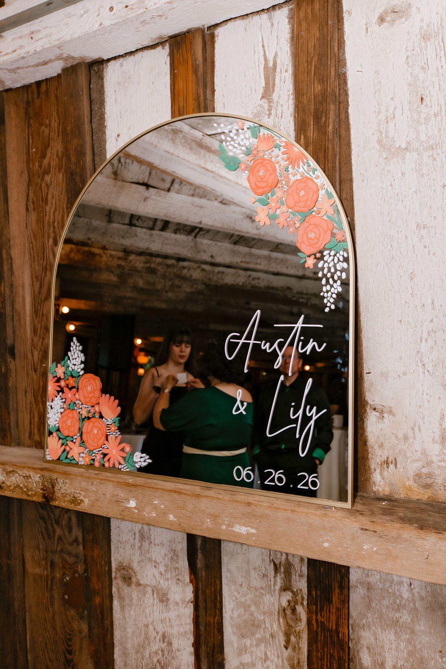 Arched mirror wedding welcome sign for Austin and Lily dated 06.26.26 with floral decorations.