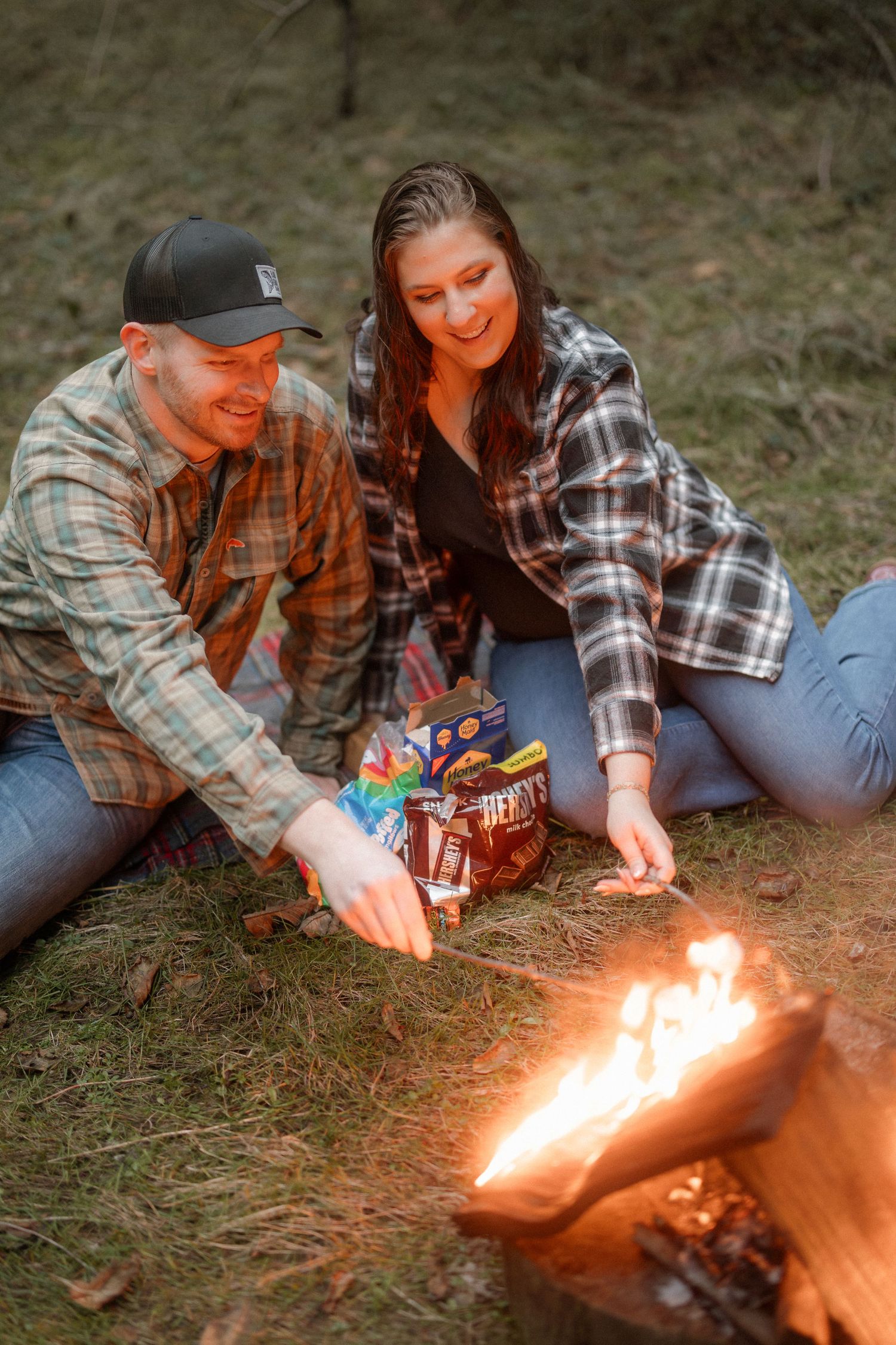 Couple roasting marshmallows over a campfire while enjoying an outdoor evening together.