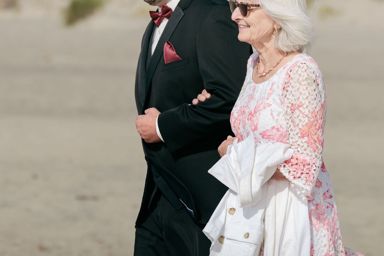 Wedding party in formal attire posing together against neutral background.