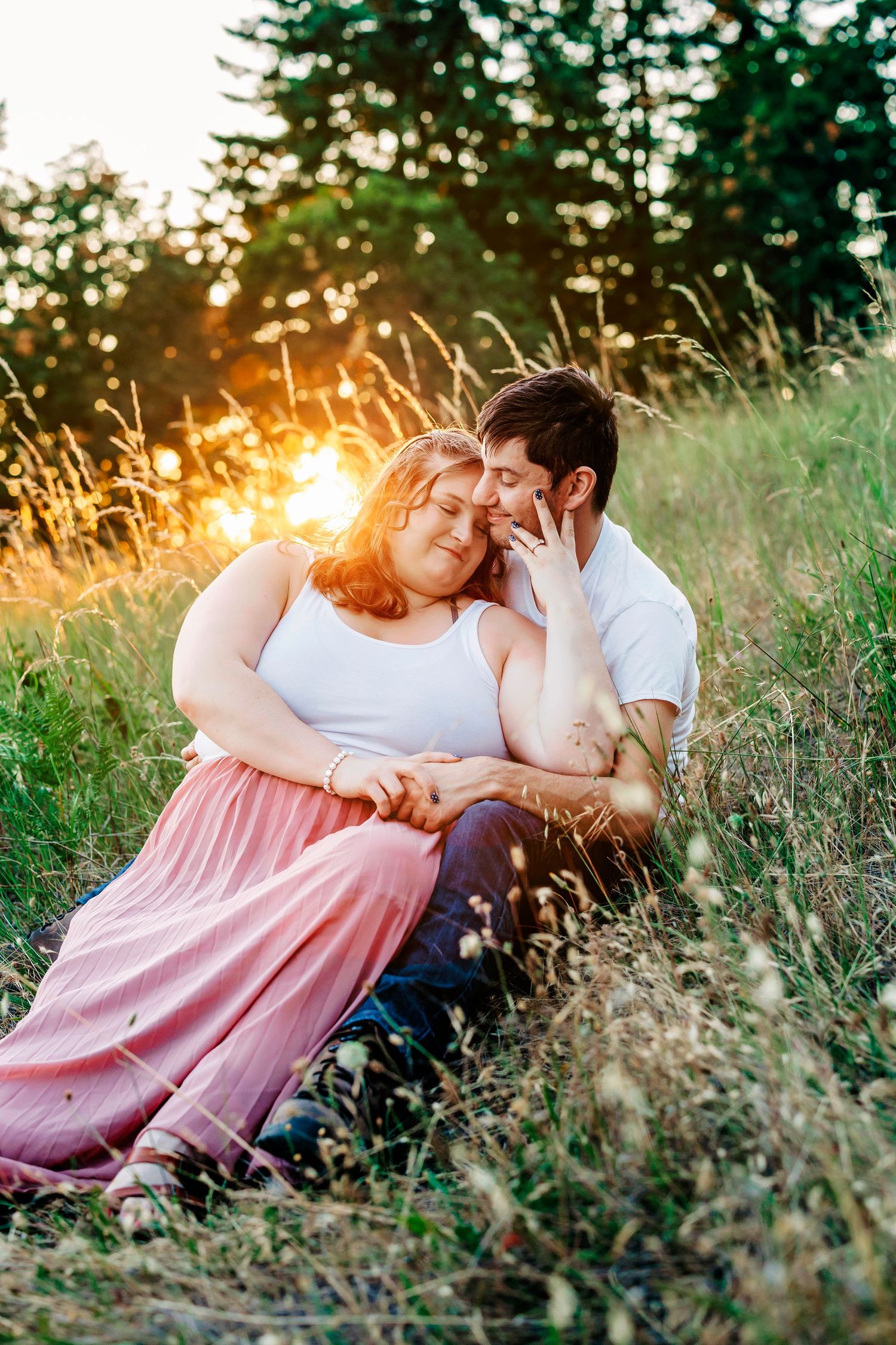 A couple sharing an intimate moment in a grassy field during golden hour sunset.
