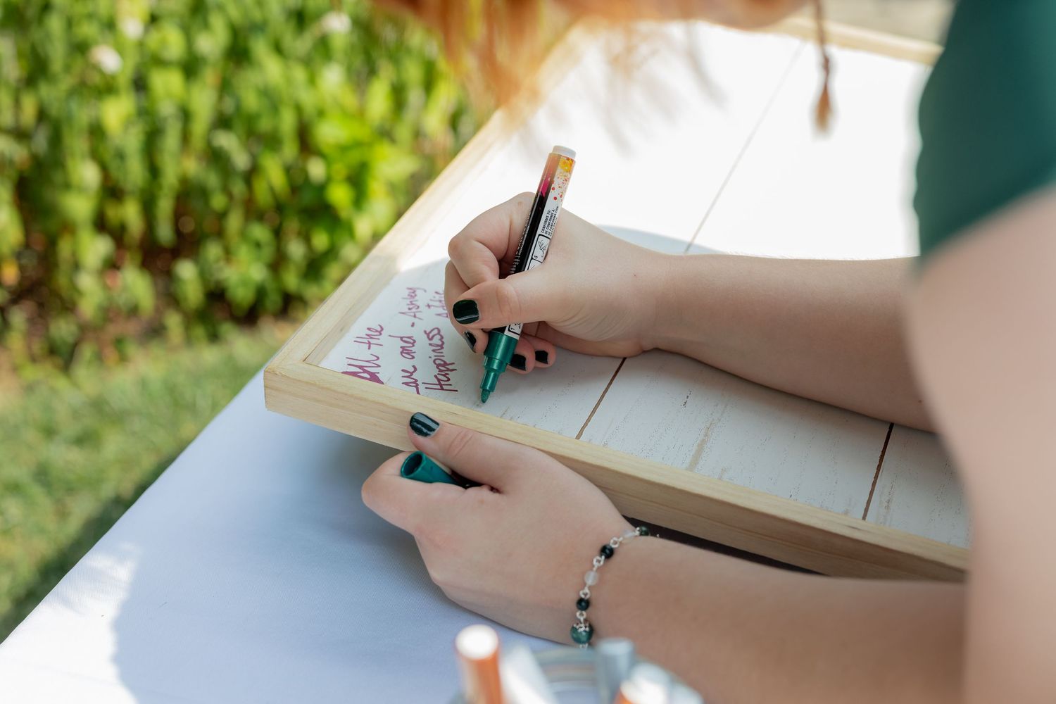 Close-up of hands writing in a notebook or journal with a pen on white paper.