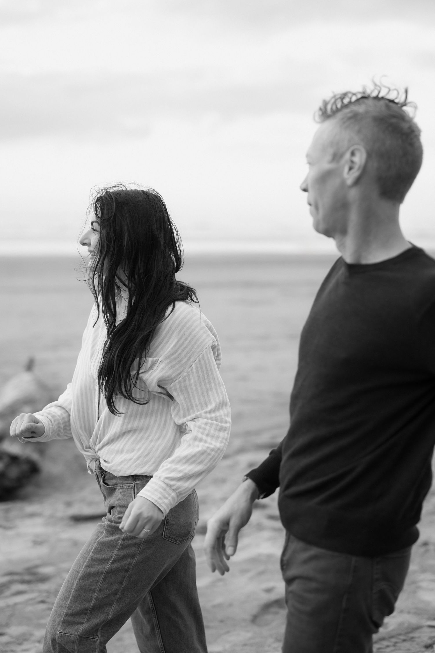 Black and white photo series of a couple dancing playfully together on a beach at sunset.