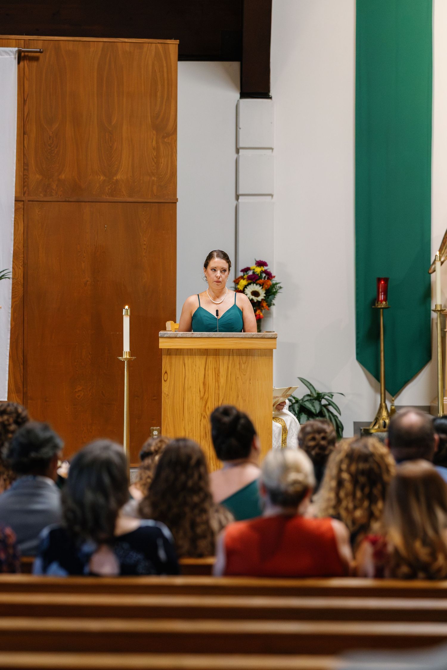 A speaker addresses wedding guests from a wooden podium in a church setting.
