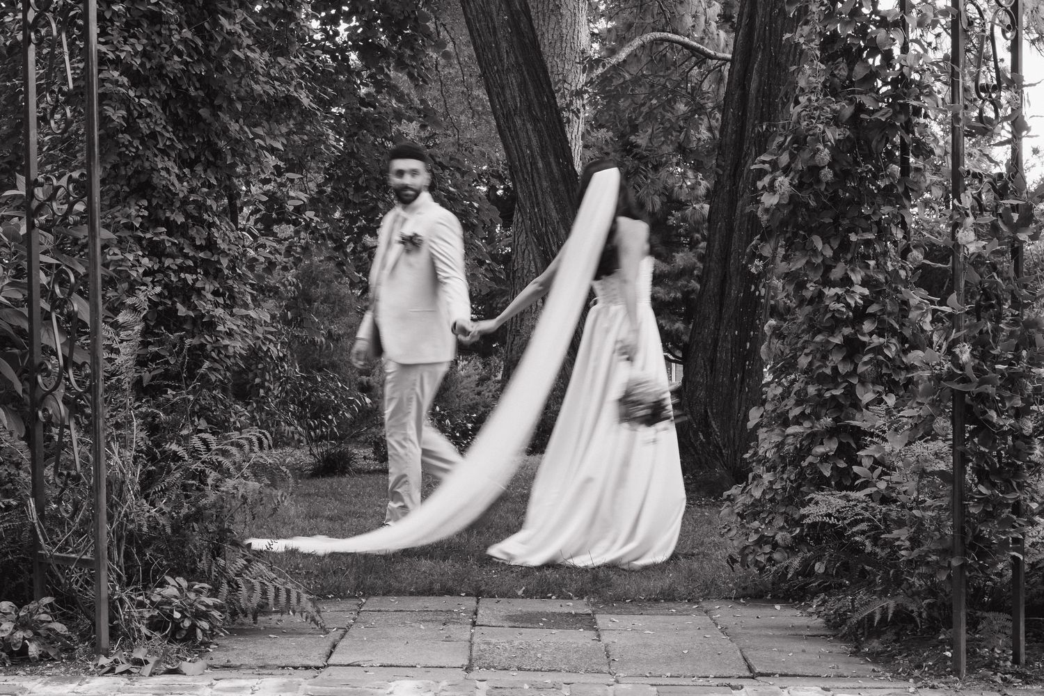 Black and white wedding photos capturing romantic moments in garden pathway setting.