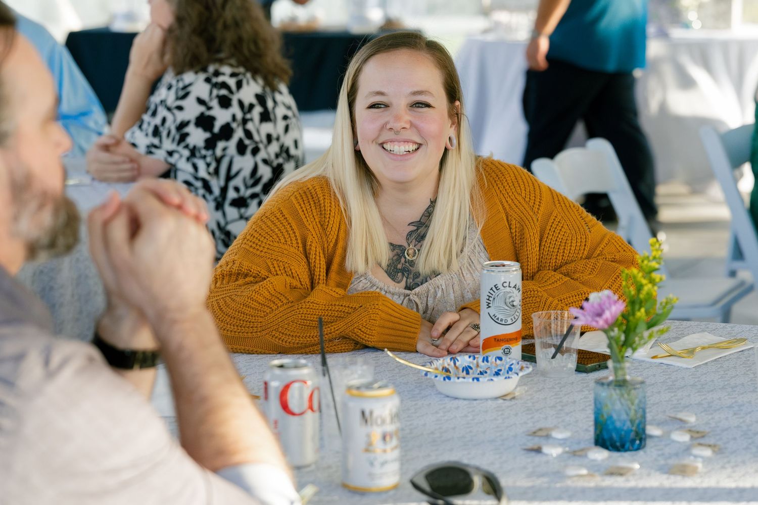 Wedding reception guests seated at outdoor tables under a tent enjoying a celebration.
