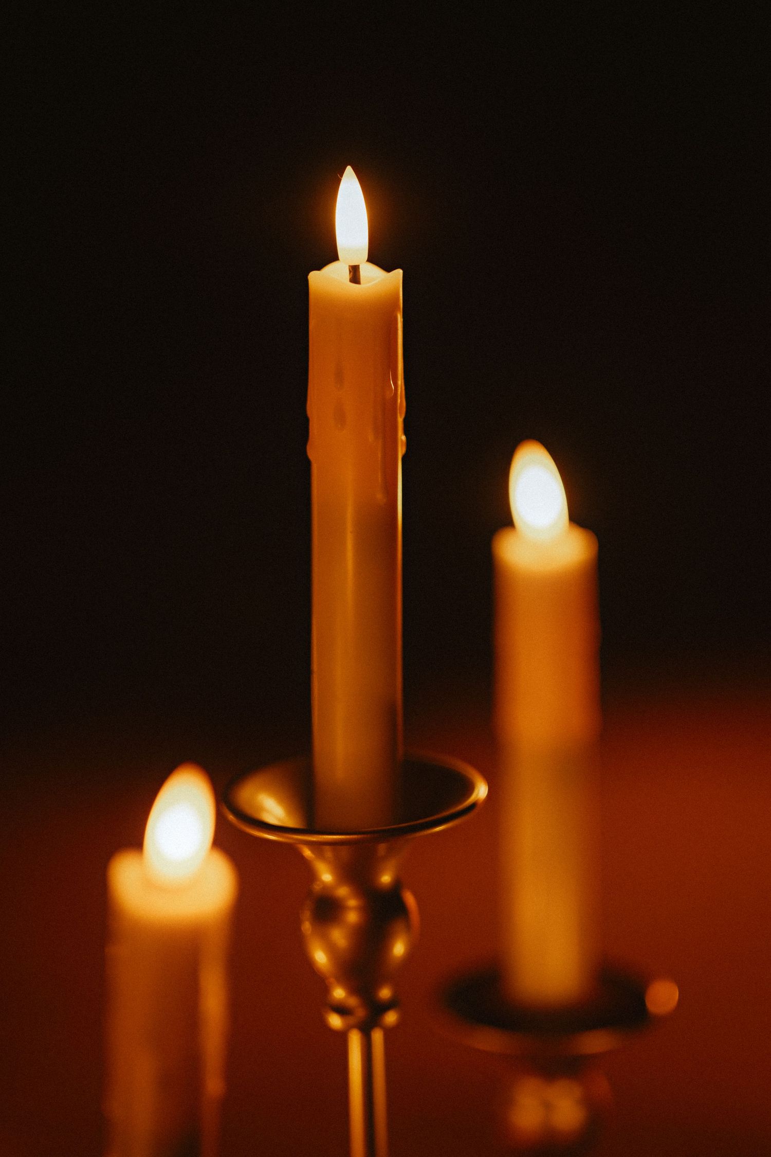 Close-up of burning white candles against a dark background creating a warm, intimate atmosphere.