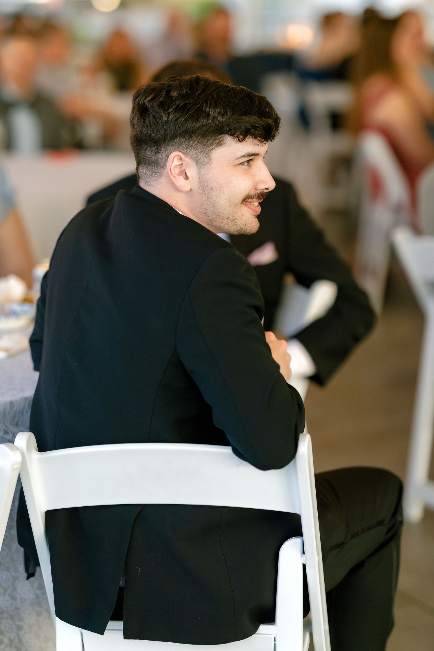 Person in a black suit sitting at a wedding reception table in a candid sequence of photos.
