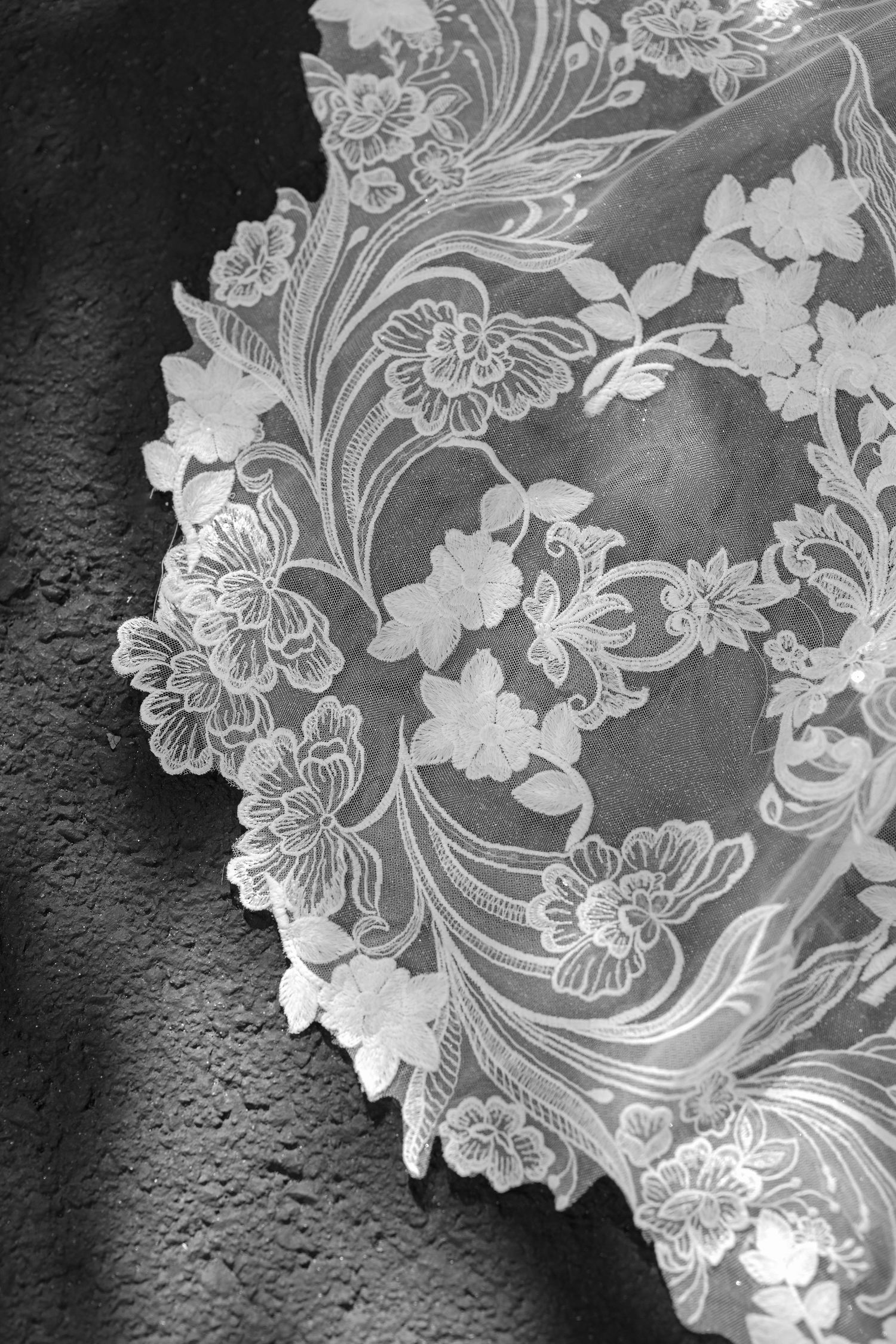 Delicate white lace fabric with intricate floral patterns and scalloped edges shown in black and white detail shots.